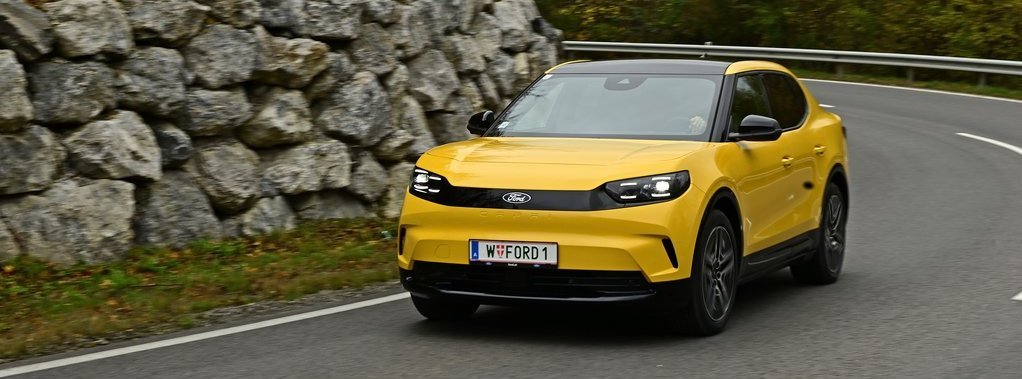 gelber Ford Capri fährt auf einer straße durch Laubwald